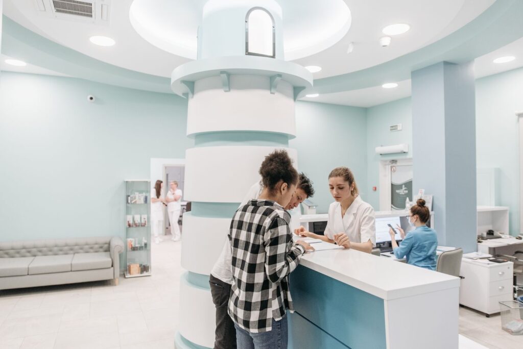 Recepção de clínica com pacientes sendo atendidos pela equipe