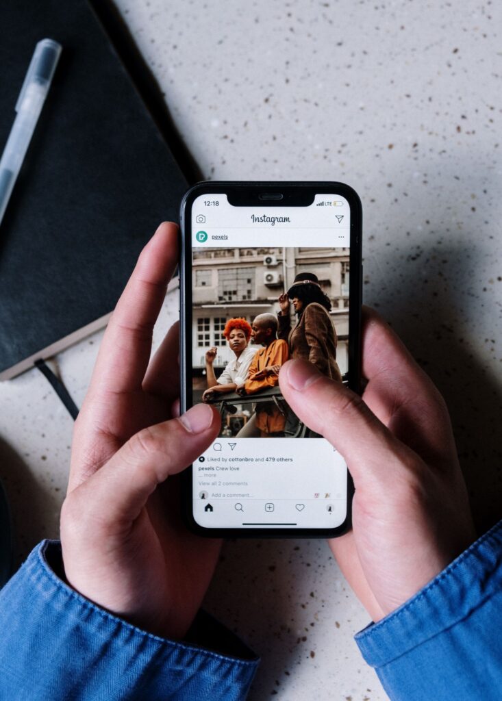 Mão segurando celular com perfil do Instagram aberto
